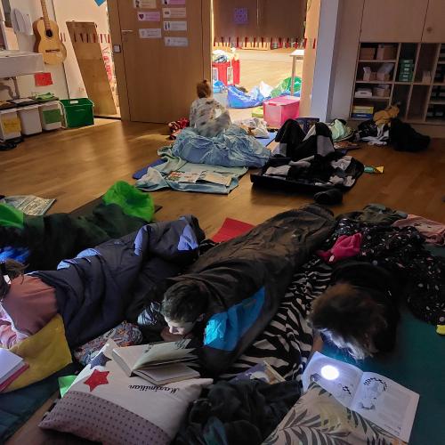 Kinder in Schlafsäcken lesen mit Taschenlampen